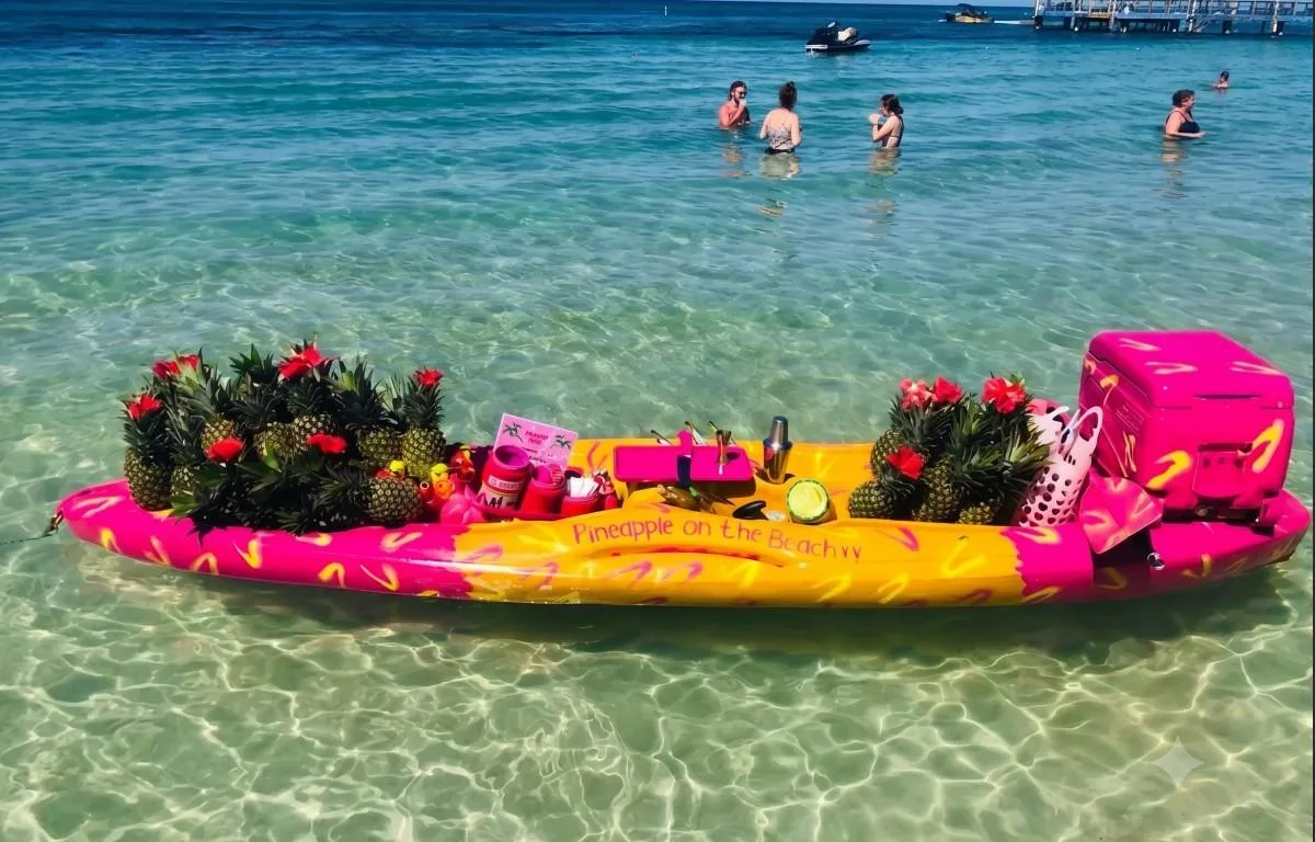 Kayak rosa y amarillo flotando con piñas decoradas en West Bay Roatán